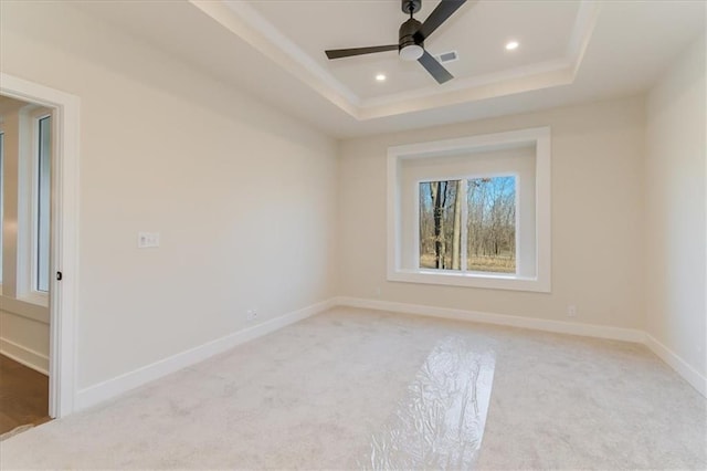 empty room with light colored carpet, baseboards, a raised ceiling, and recessed lighting