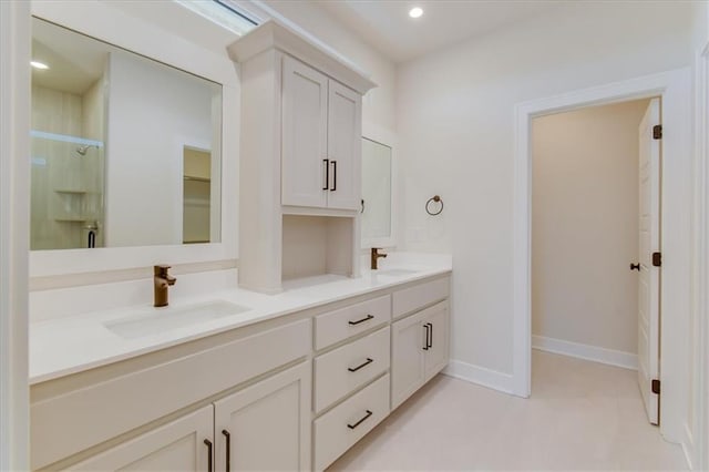 bathroom with double vanity, baseboards, a shower stall, a sink, and recessed lighting