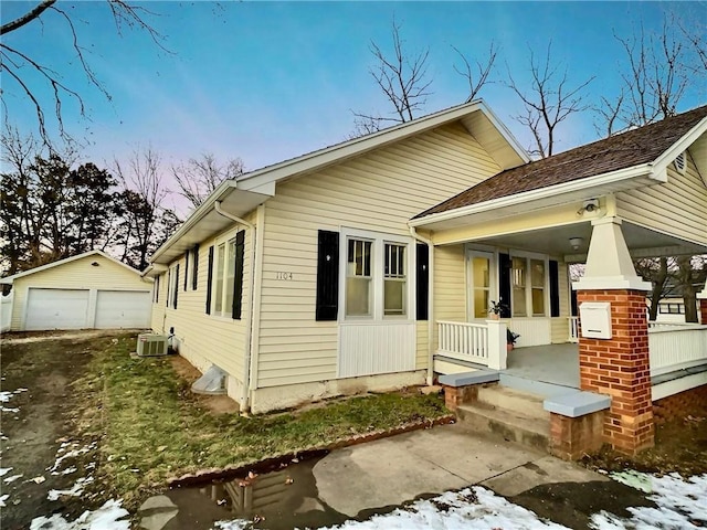 view of front of home with covered porch, cooling unit, a garage, and an outdoor structure