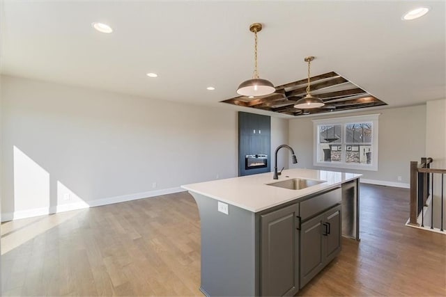 kitchen with open floor plan, light countertops, light wood-type flooring, and a sink