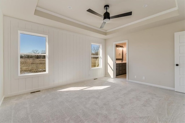 unfurnished bedroom with ornamental molding, a tray ceiling, visible vents, and light carpet