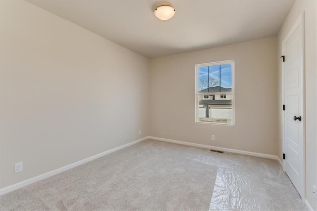 empty room featuring light carpet, visible vents, and baseboards