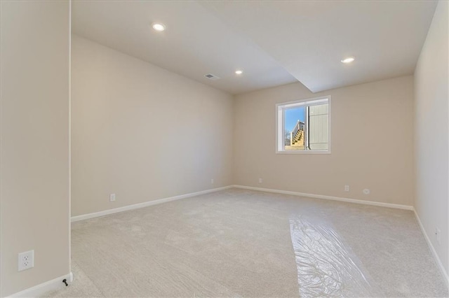 spare room featuring light carpet, recessed lighting, visible vents, and baseboards