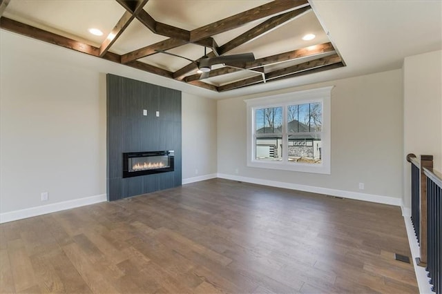 unfurnished living room featuring dark wood-style floors, beam ceiling, a fireplace, coffered ceiling, and baseboards