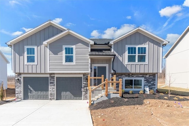 split foyer home featuring concrete driveway, board and batten siding, a standing seam roof, a garage, and stone siding