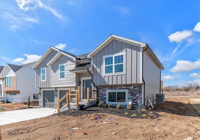 split foyer home with a garage, central AC, stone siding, driveway, and board and batten siding