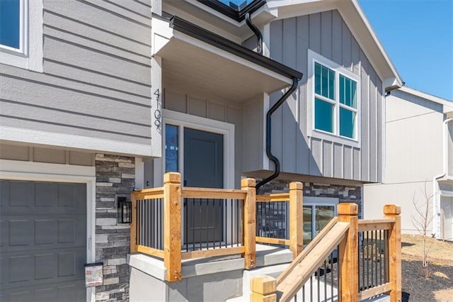 doorway to property with a garage, stone siding, and board and batten siding