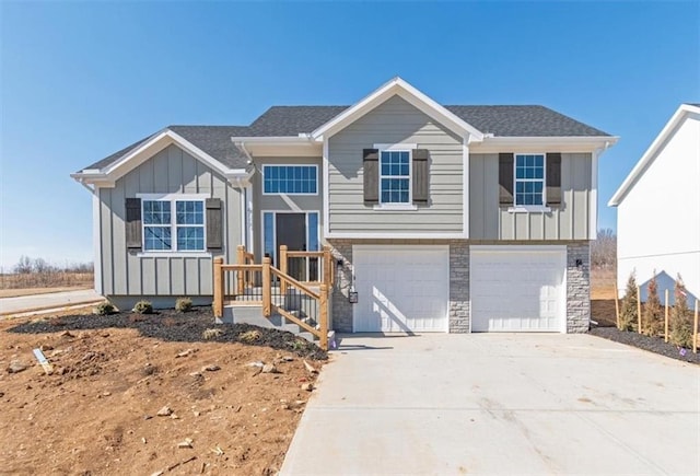 view of front of home with a garage, concrete driveway, stone siding, roof with shingles, and board and batten siding