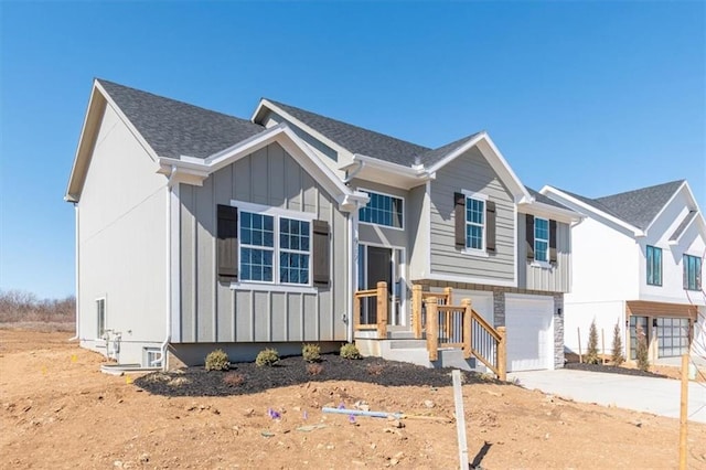 view of front of property with an attached garage, concrete driveway, stone siding, roof with shingles, and board and batten siding