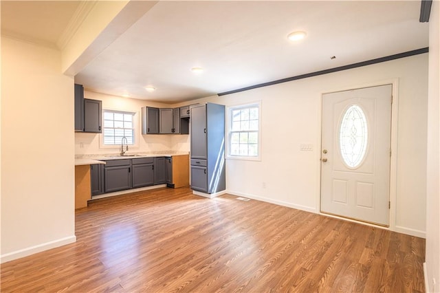 kitchen with crown molding, light hardwood / wood-style floors, decorative backsplash, and gray cabinetry