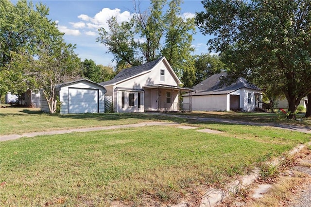 view of front of house with a garage, an outbuilding, a front lawn, and covered porch