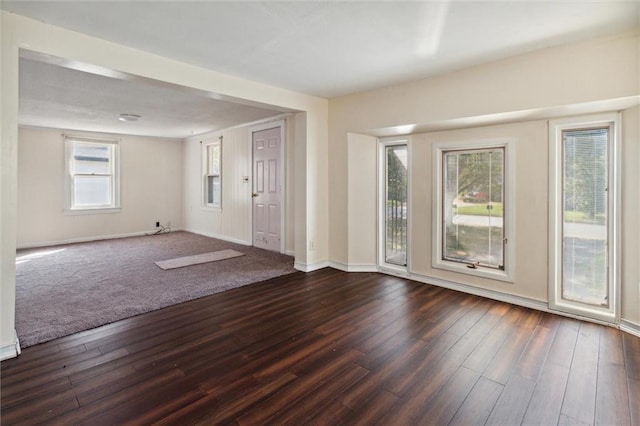 spare room with a wealth of natural light and dark wood-type flooring