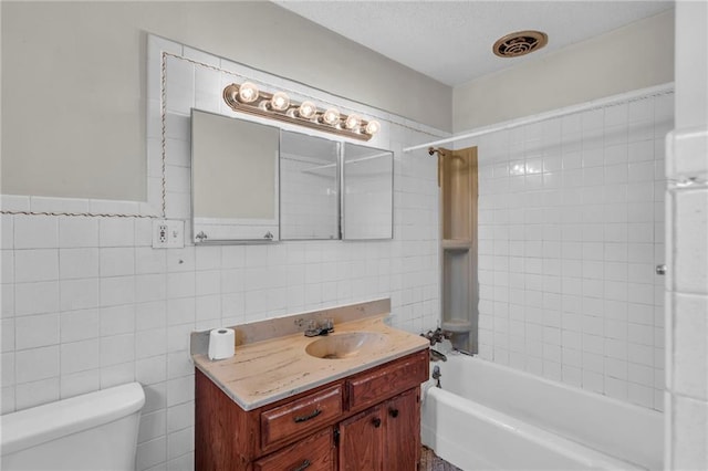 full bathroom with tile walls, vanity, toilet, and tiled shower / bath