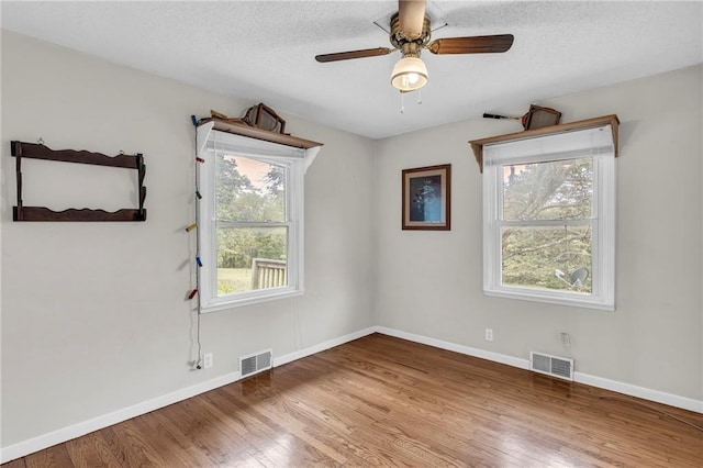 spare room with ceiling fan, hardwood / wood-style flooring, and a textured ceiling