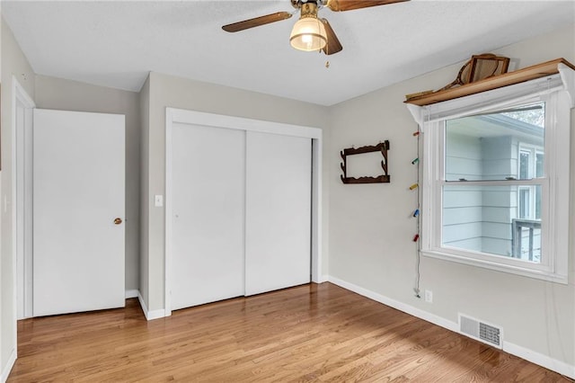 unfurnished bedroom with light hardwood / wood-style floors, ceiling fan, and a closet