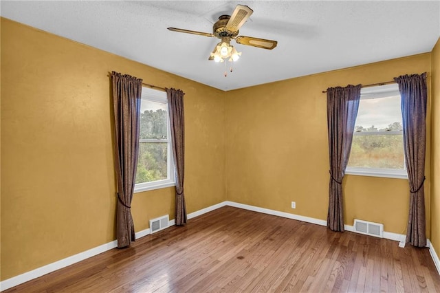 spare room with ceiling fan, hardwood / wood-style flooring, and plenty of natural light