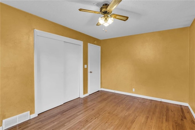 unfurnished bedroom with a closet, wood-type flooring, and ceiling fan