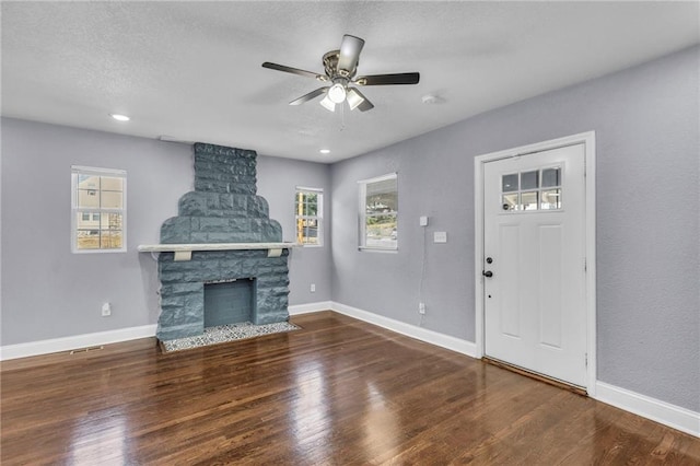 entrance foyer with a wealth of natural light, ceiling fan, wood-type flooring, and a fireplace