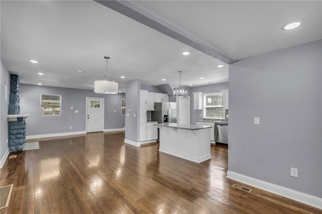 kitchen with dark wood-type flooring, white cabinets, stainless steel appliances, a center island, and decorative light fixtures