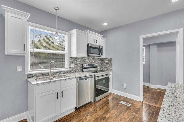 kitchen featuring dark wood-type flooring, sink, white cabinets, decorative backsplash, and appliances with stainless steel finishes