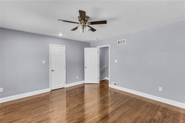 unfurnished bedroom with a textured ceiling, dark hardwood / wood-style floors, and ceiling fan