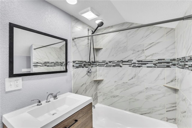 bathroom featuring tiled shower / bath combo, lofted ceiling, and vanity