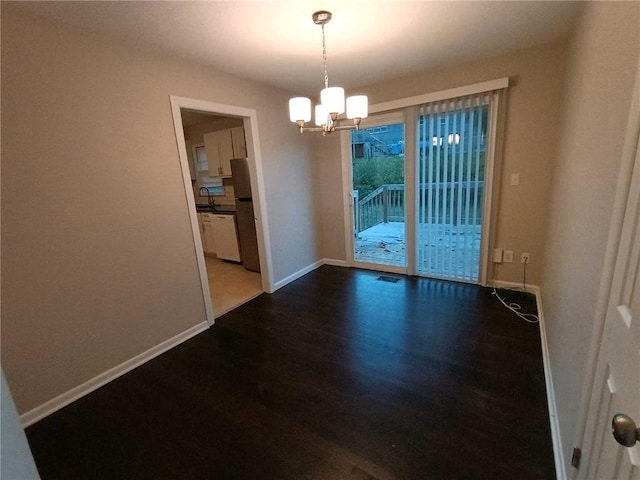 unfurnished dining area with a notable chandelier, dark wood-type flooring, and sink