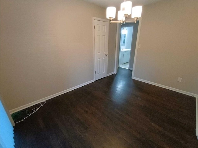 spare room featuring dark hardwood / wood-style floors and a chandelier