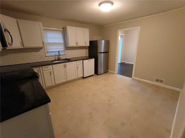 6914 Rowland Ave, Kansas City, KS 66109 - kitchen with visible vents, white dishwasher, a sink, freestanding refrigerator, and decorative backsplash