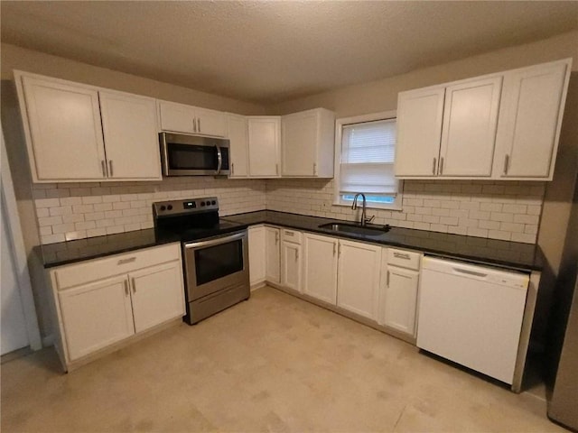 6914 Rowland Ave, Kansas City, KS 66109 - kitchen with white cabinetry, backsplash, dark countertops, stainless steel appliances, and a sink