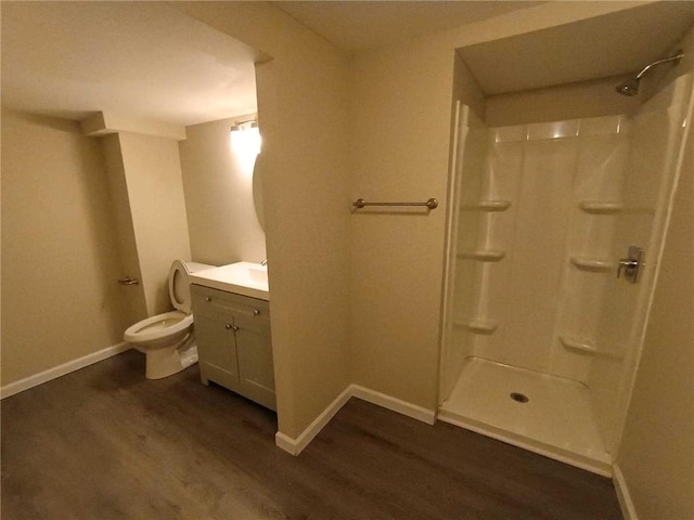 bathroom with hardwood / wood-style floors, walk in shower, vanity, and toilet