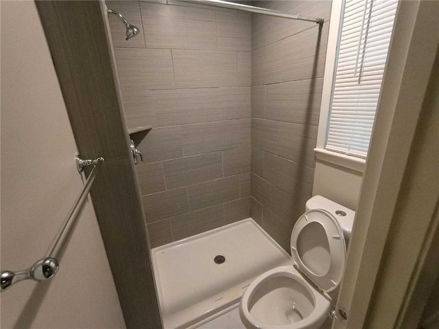 bathroom featuring tiled shower and toilet