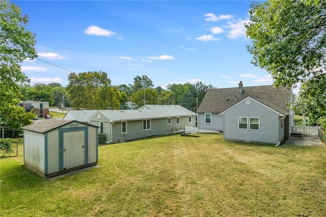 rear view of property featuring a lawn and a storage unit