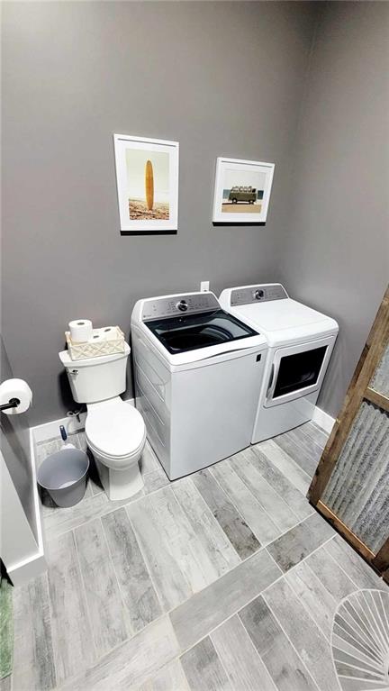 bathroom with washer and clothes dryer, toilet, and wood-type flooring