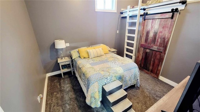 bedroom with a barn door and dark colored carpet