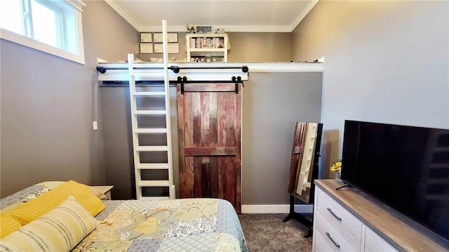 bedroom featuring a barn door, ornamental molding, and dark colored carpet