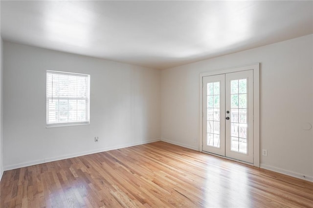 spare room with french doors, light wood-style flooring, and baseboards