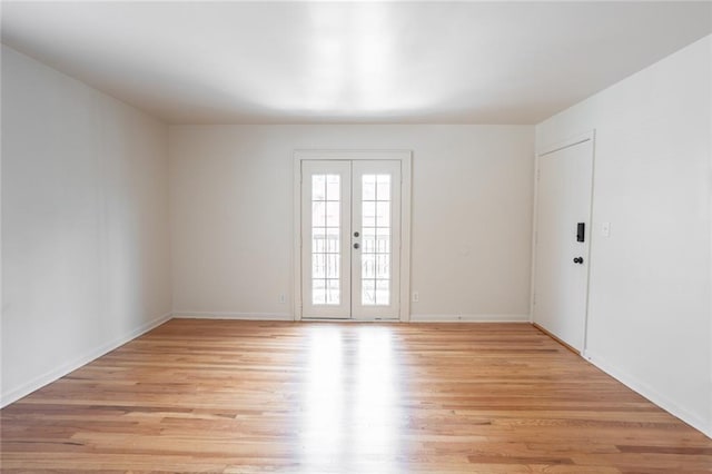 empty room featuring french doors and light hardwood / wood-style flooring