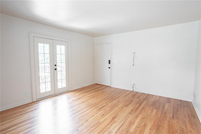 unfurnished room featuring light wood-style floors, french doors, and baseboards