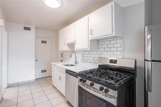 kitchen featuring stainless steel appliances, a sink, decorative backsplash, light countertops, and white cabinetry