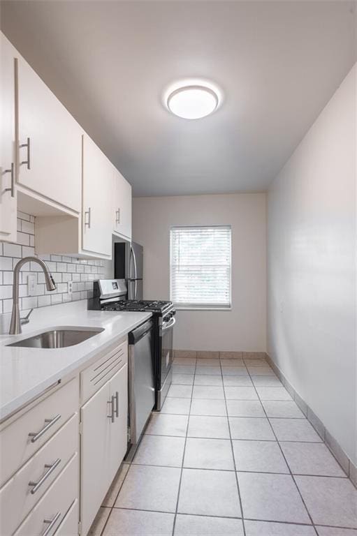 kitchen featuring a sink, stainless steel appliances, light countertops, light tile patterned flooring, and white cabinetry