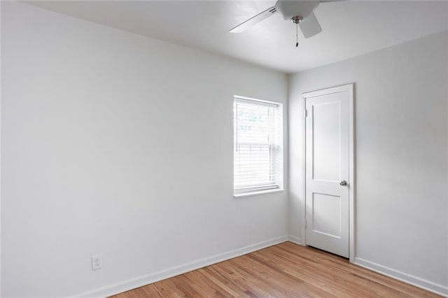 empty room with baseboards, ceiling fan, and light wood-style flooring
