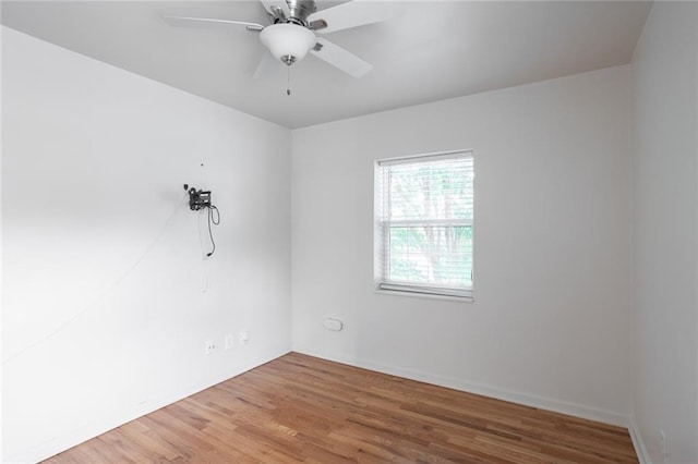 unfurnished room with wood finished floors, a ceiling fan, and baseboards
