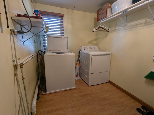 clothes washing area with washer and clothes dryer and light hardwood / wood-style flooring