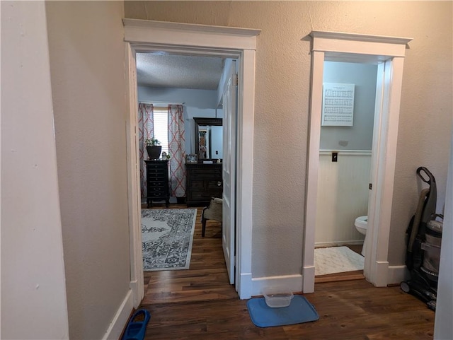 corridor featuring a textured ceiling and dark hardwood / wood-style flooring