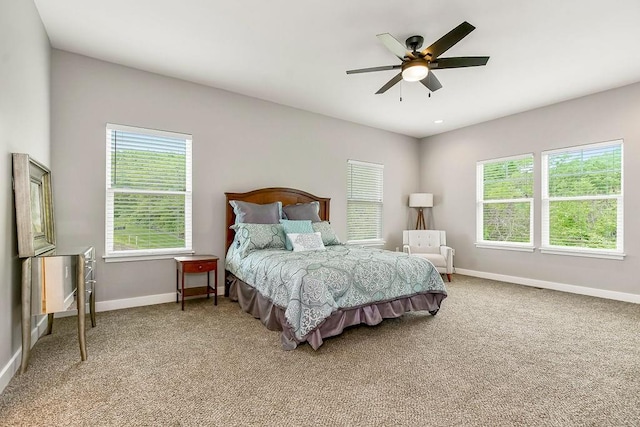 carpeted bedroom featuring baseboards, ceiling fan, and multiple windows