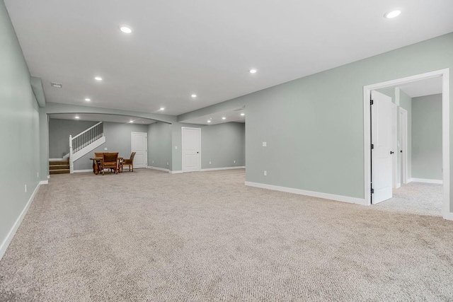 interior space featuring recessed lighting, stairway, baseboards, and light carpet