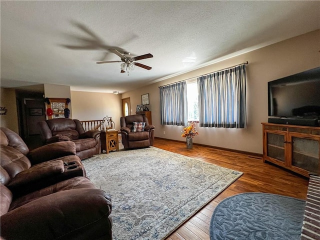 living room featuring ceiling fan, hardwood / wood-style flooring, and a textured ceiling