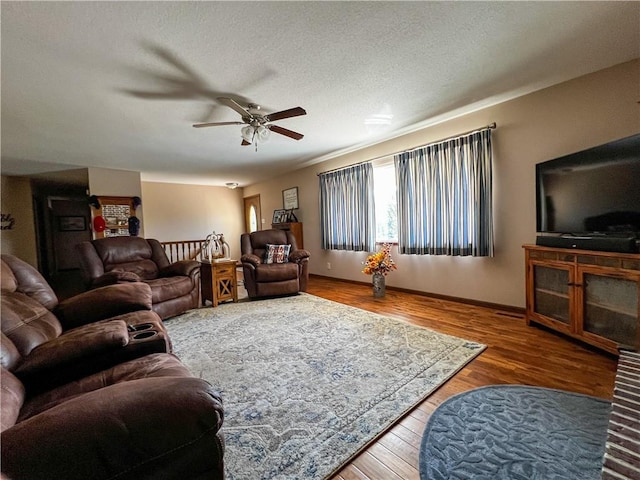 living room with ceiling fan, wood finished floors, and a textured ceiling