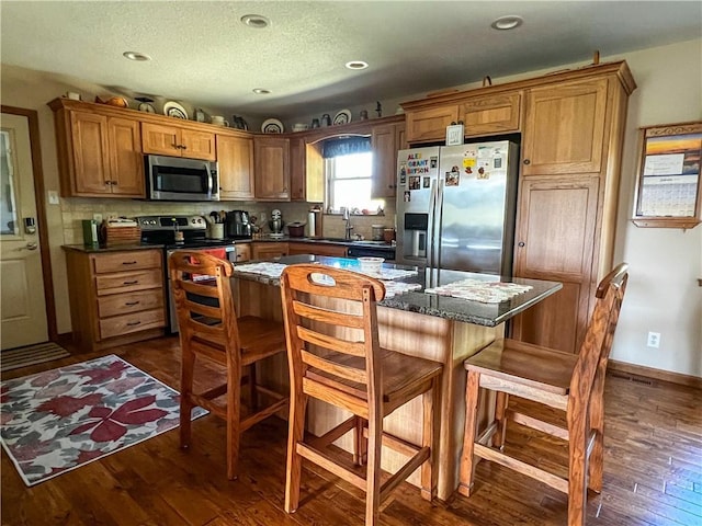 kitchen featuring a breakfast bar, tasteful backsplash, a kitchen island, dark hardwood / wood-style flooring, and stainless steel appliances